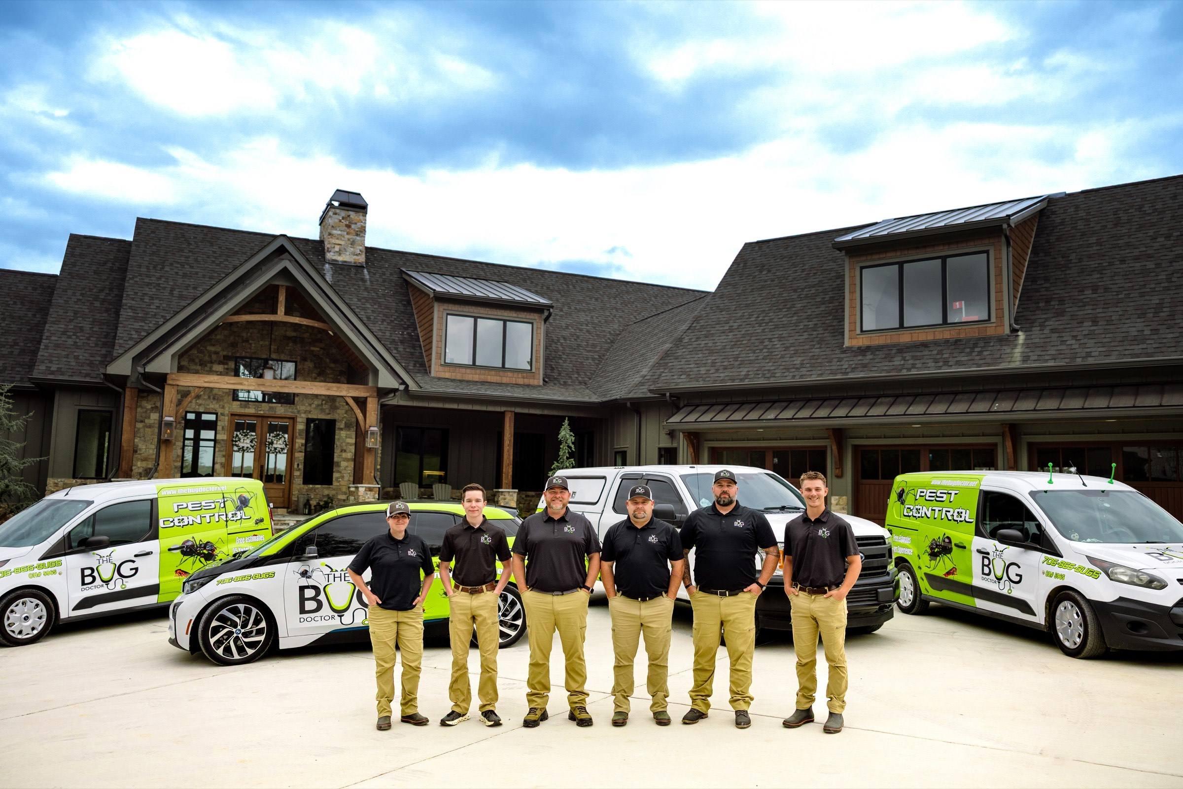 The Bug Doctor team standing with branded pest control vehicles